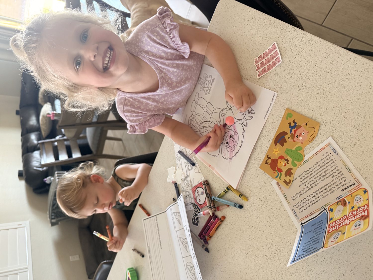 Two young children smiling while coloring their Mailbox Wonders activity sheets